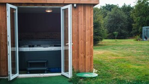 Een houten constructie met een glazen deur die leidt naar een kamer met een bed en een bank.