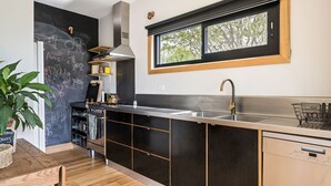 A modern kitchen with a black backsplash, stainless steel appliances, and a window above the sink. - One Bright Stay in beautiful Bright (Bright)