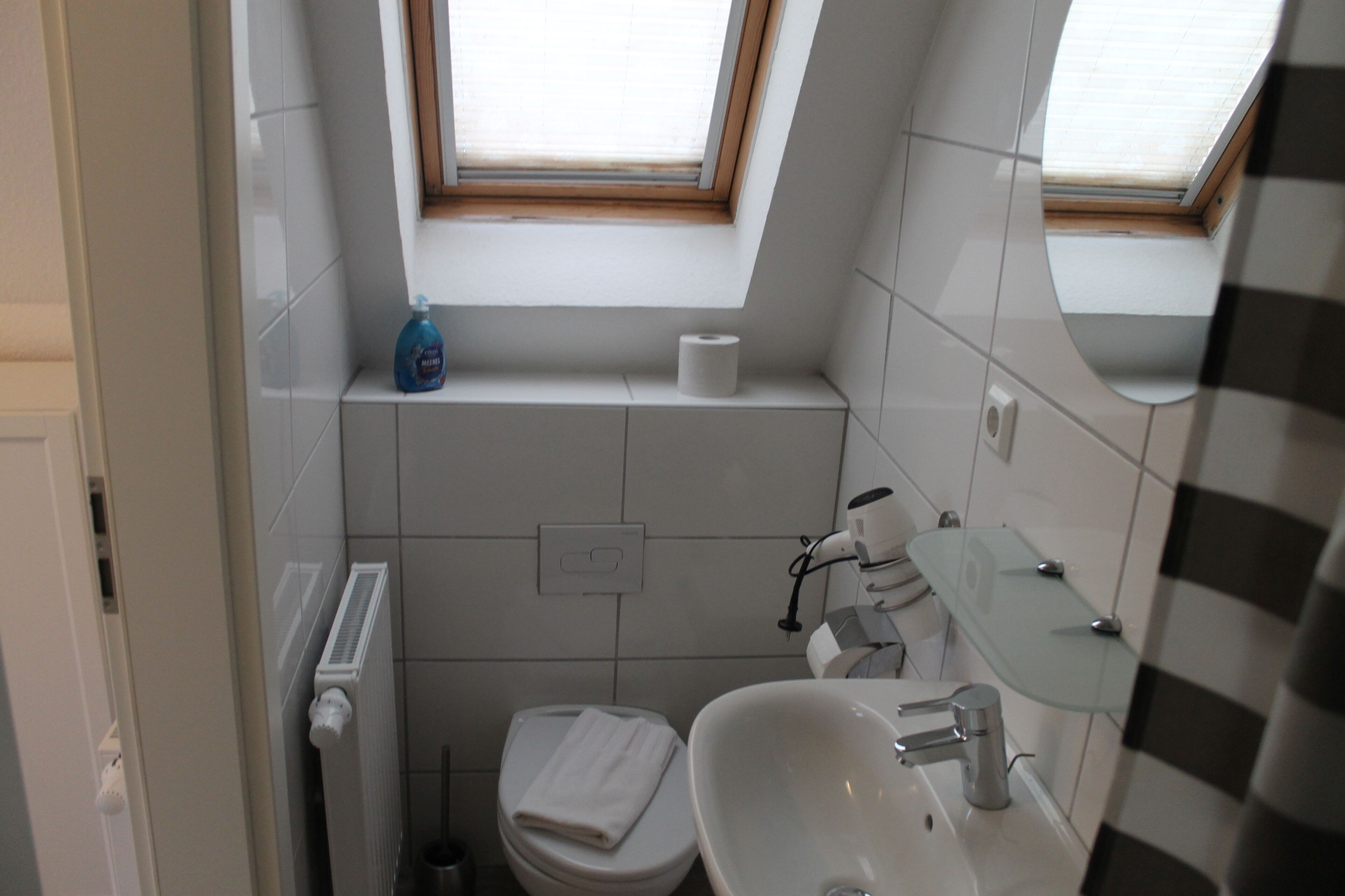A small bathroom with a toilet, sink, and a window above the toilet.