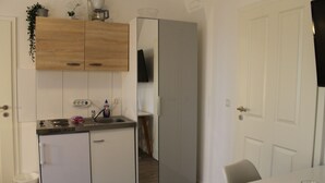 A compact kitchen with a refrigerator, sink, and cabinets. - Apartment am Wall (Emden)