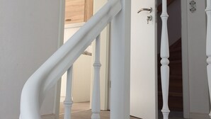 A white staircase with a wooden handrail leading to a door. - Apartment am Wall (Emden)