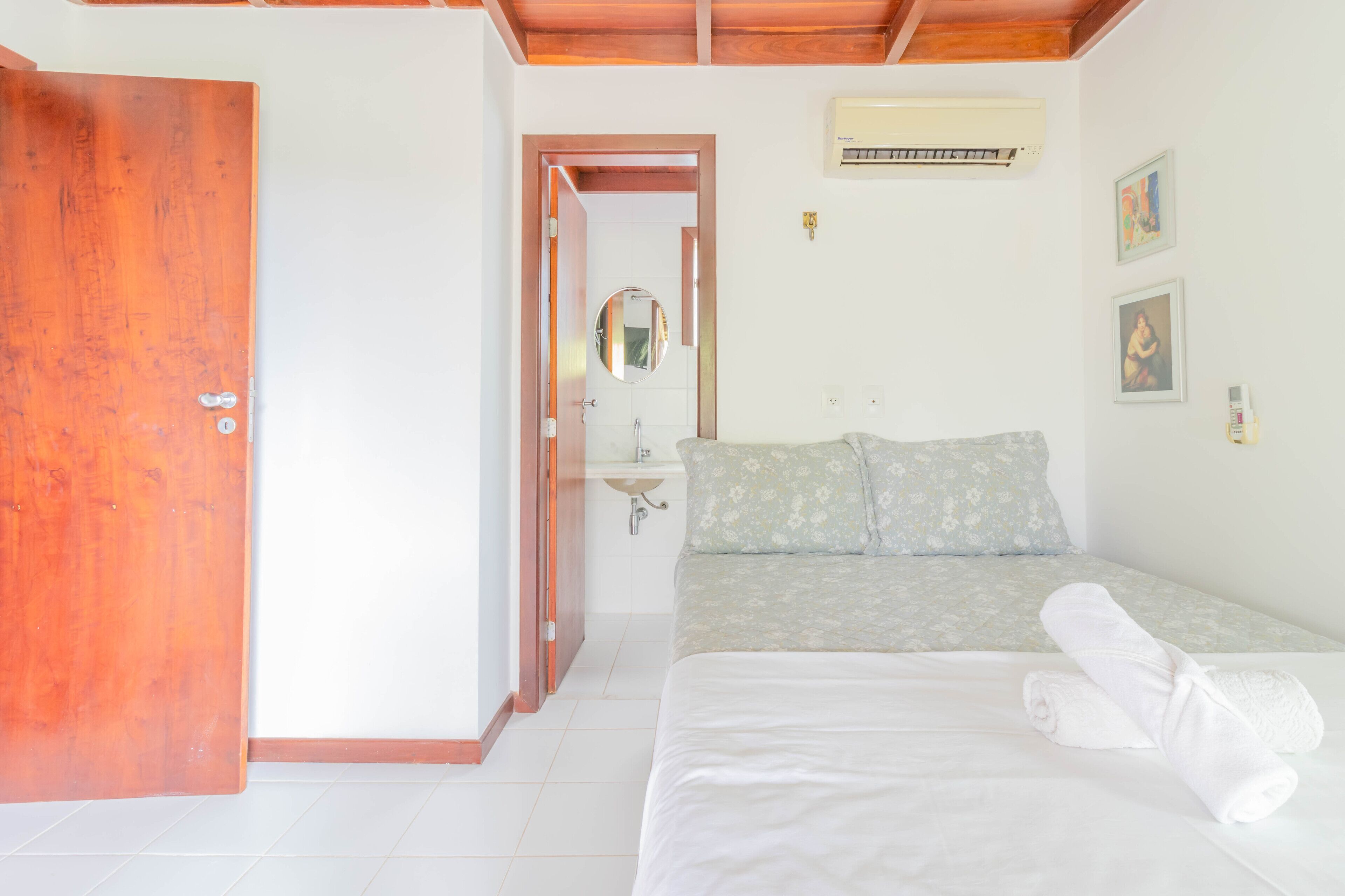 A bedroom with a bed, a bathroom with a sink, and a door.