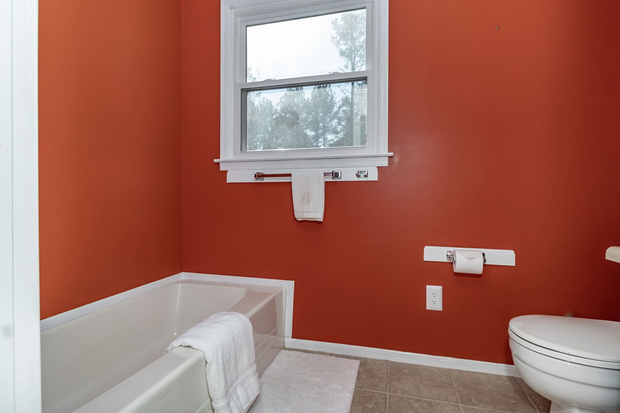 Une salle de bain avec une baignoire, des toilettes et une fenêtre.