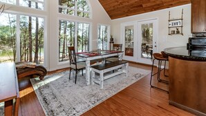 Una cocina espaciosa con una isla grande, techo de madera y ventanas amplias que ofrecen vistas al bosque.