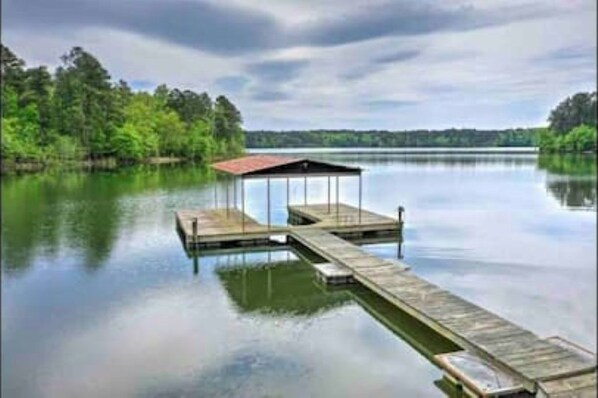 Un muelle de madera que se extiende sobre aguas tranquilas con un refugio cubierto.