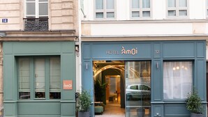 A hotel entrance with a green facade, a sign reading "Hôtel Aamoi 12", and two potted plants outside. - Hôtel Amoi Paris (Paris)