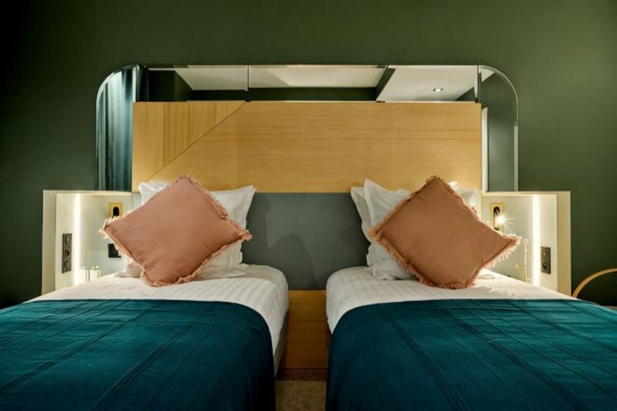 A double bed with two pillows, a wooden headboard, and bedside tables with lamps.