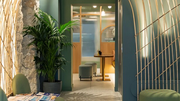 An interior with a curved metal structure, seating area, and a potted plant. - Hôtel Amoi Paris (Paris)