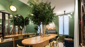 A bar area with wooden furniture, a large mirror, and a tree centerpiece. - Hôtel Amoi Paris (Paris)