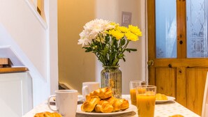 Ein Frühstückstisch mit Croissants, einem Blumenstrauß und Orangensaft.