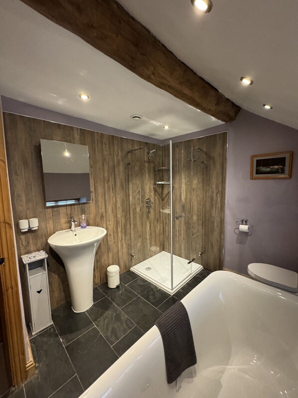 Un baño moderno con una bañera independiente, un lavabo pedestal y una ducha con mampara de vidrio.