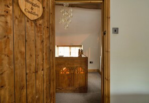 Un interior de madera con un letrero que dice 'Snuggles & Cuddles', un mueble de madera con detalles curvos y una lámpara de araña.