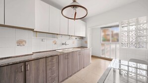 A modern kitchen with white cabinets, a granite countertop, a double sink, and a large window with frosted glass panels.