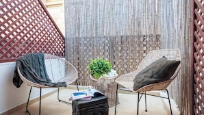 A balcony with two wicker chairs, a small round table, and a potted plant.