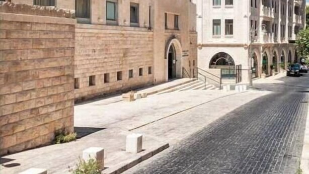 A building with a modern facade, a prominent logo, and a cobblestone street.