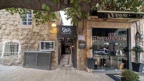 A stone building with a modern shop entrance, a metal gate, and a potted plant.