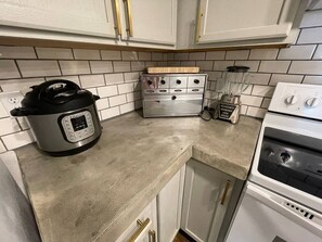 A kitchen with a built-in oven, a stovetop, and a countertop with a slow cooker and a blender.