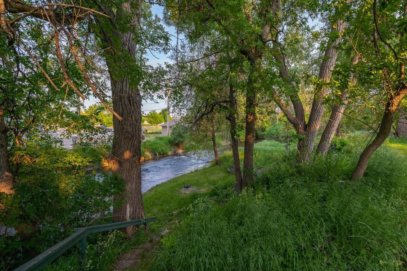 A natural landscape with a river, trees, and a path.