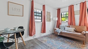 A room with a round dining table, a sofa, a lamp, and a rug.