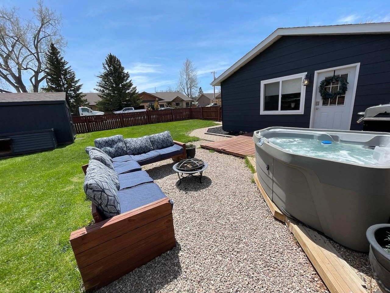 Un patio trasero con jacuzzi, terraza de madera y sofá modular.
