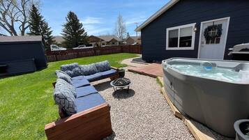 A backyard with a hot tub, a wooden deck, and a sectional sofa.