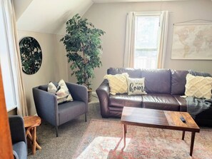 A cozy living room with a grey armchair, a brown leather sofa, and a coffee table.