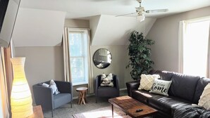 Una sala de estar con sofá, sillón, mesa de centro y un espejo grande.