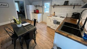 Una cocina con una mesa de comedor, sillas, un refrigerador, un microondas, una estufa y un lavabo.