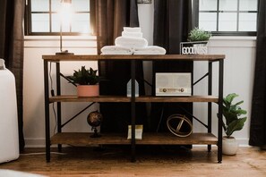 A wooden shelf with folded white towels, a vintage radio, and potted plants. - Cottage #2 - Spearfish Orchard Creek Cottages (Spearfish)