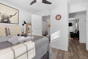 A bedroom with a bed, a clock, and a door leading to another room. - Cottage#6 - Spearfish Orchard Creek Cottages (Spearfish)