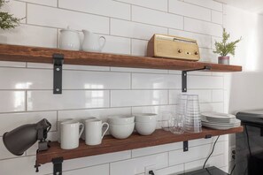 A kitchen with two wooden shelves, white tiles, and various kitchenware. - Cottage#6 - Spearfish Orchard Creek Cottages (Spearfish)