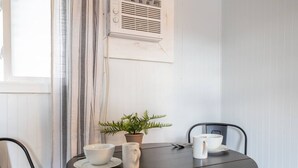 A round table with a white mug, a white cup, and a white bowl on a saucer. There is a potted plant on the table. - Cabin #11 - Spearfish Orchard Creek Cottages (Spearfish)