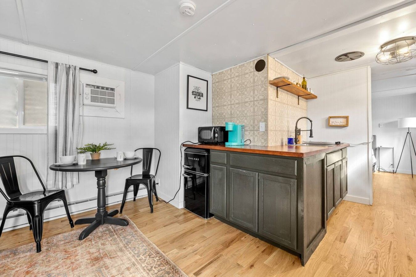 A compact kitchen with a central island, a dining area with two chairs, and a small table.