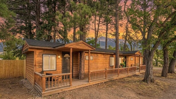 A cabin with a porch, a door, and a window. - Cabin #11 - Spearfish Orchard Creek Cottages (Spearfish)