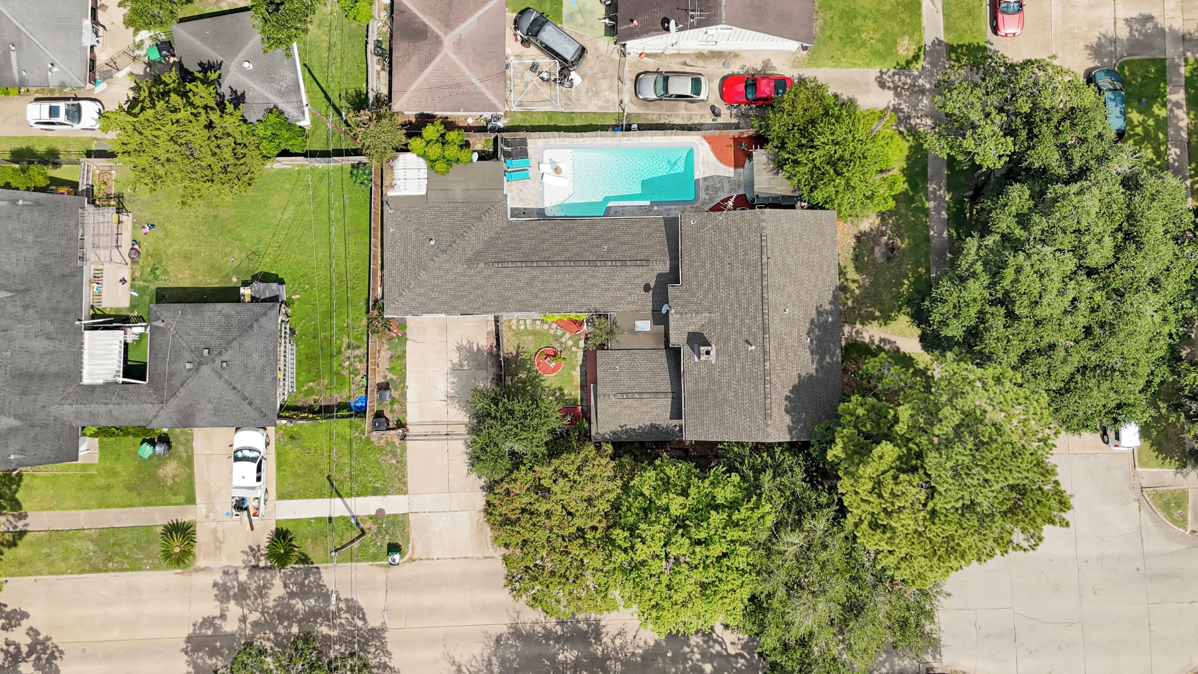 An aerial view of a residential area with a swimming pool, houses, and a green lawn.