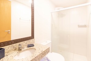 Une salle de bain équipée d’un lavabo, d’un miroir, de toilettes et d’une douche.