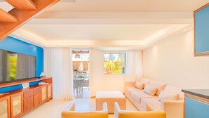 A modern living room with a TV, sofa, and yellow chairs. - IT32 Triplex 4 Suítes a 100m da Praia (Camaçari)