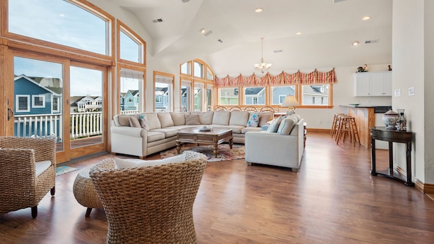 A spacious living room with a large sectional sofa, wicker chairs, and a dining area with wooden chairs and a table.