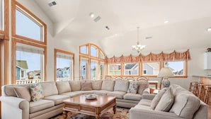 A spacious living room with a large sectional sofa, a coffee table, and a dining area with a chandelier.