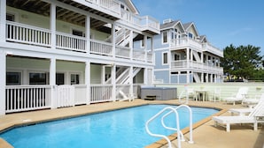 A two-story building with a swimming pool, outdoor seating, and a hot tub.