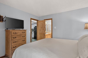 A bedroom with a bed, wooden dresser, and a television on top.