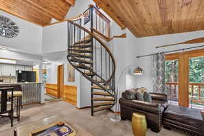 Un vaste espace de vie agrémenté d’un escalier en colimaçon, d’un canapé en cuir et d’une cuisine située au fond de la pièce.