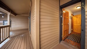A wooden deck with a wooden door leading to a room.