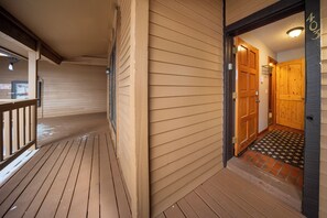 Une terrasse en bois avec une porte en bois donnant sur une pièce.