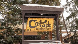 A wooden sign with the text "Creekside 145 of Winter Park" in a yellow and black color scheme.