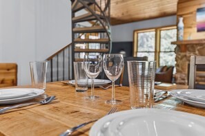 A dining table set with plates, cutlery, and glasses, with a staircase and a window in the background. - Creekside Unit 403 Spacious 3 bedroom river views, private deck, picnic area (Winter Park)