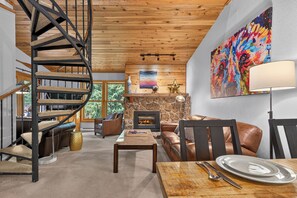 Ein modernes Interieur mit einer Wendeltreppe, einem Kamin, Ledermöbeln und einem großen, abstrakten Gemälde.
