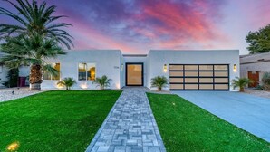 Una casa moderna de dos pisos con un camino pavimentado que conduce a un garaje.