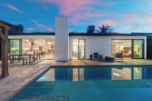 A modern house with a swimming pool, a dining area, and a living room.