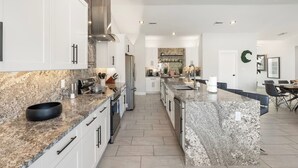 Una cocina moderna con encimeras de granito, electrodomésticos de acero inoxidable y una isla central.